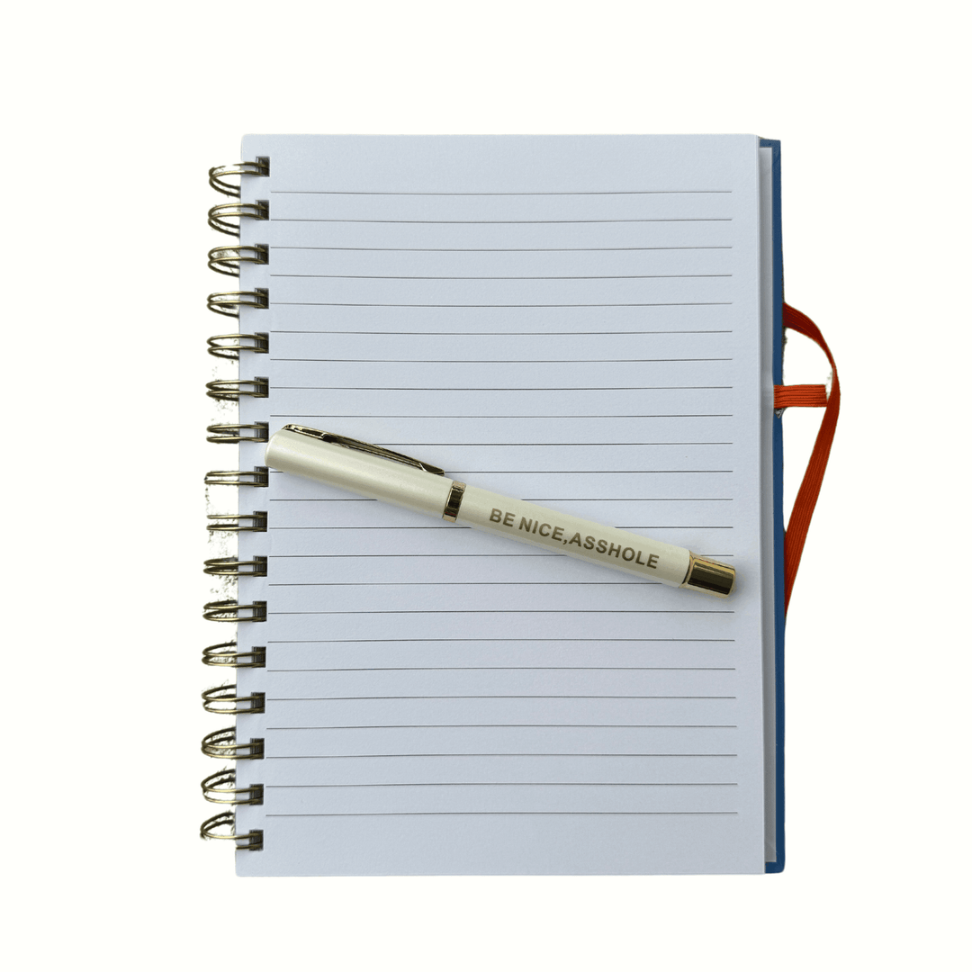 Hardcover lined journal open with included pen laying on paper
